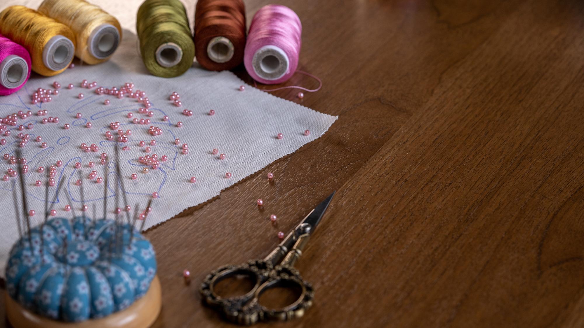 artisan arranging embroidery threads on wooden table